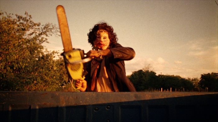 Leatherface runs at the camera wielding a chainsaw