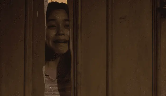 A young woman screaming in terror behind a broken door