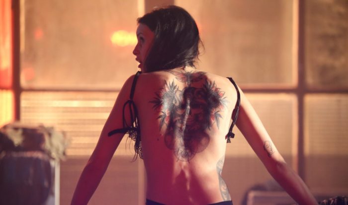 Mila is seen facing away displaying a back tattoo in Cross the Line