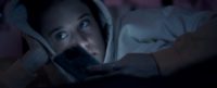 A screenshot from Ego shows Paloma (Maria Pedraza)laying in bed, idly holding her phone, lit by the light of the screen, and looking to the left