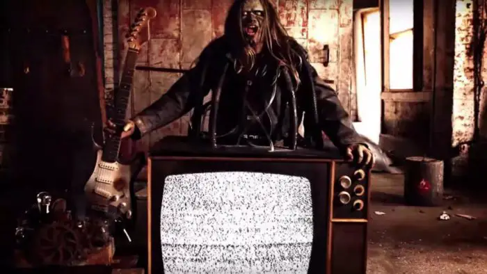 A ghoul stands behind a television set showing static in The History of Metal and Horror