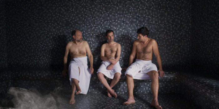 three men sit together in a sauna in Bloody Oranges