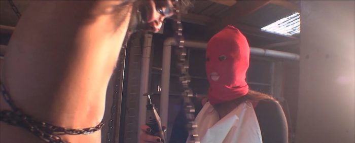 A chained up man hangs as a figure in a red hood approaches with a bone saw in Snuff Tapes