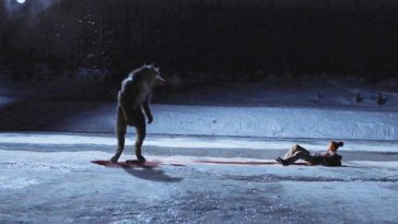 A werewolf stares down its bloody victim in the snow