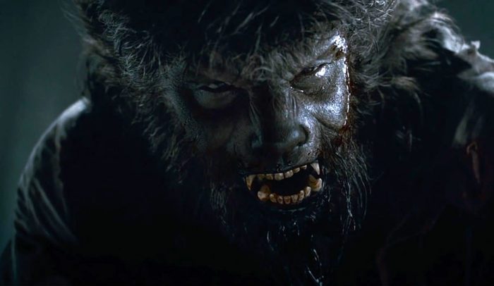 A wolfman with bloody face looks into the camera and snarls