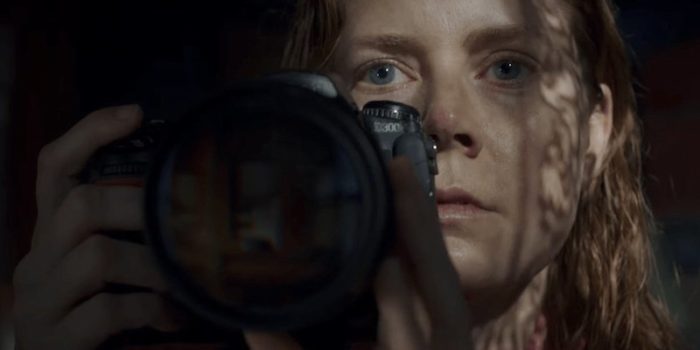 A close up of a woman holding binoculars as she looks at something in the distance.