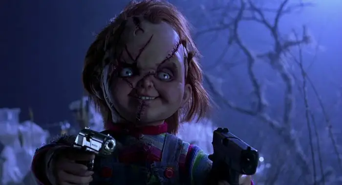 Chucky points two guns at a doomed individual.