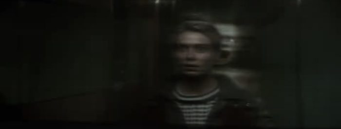 Betriek sees a presence behind her reflection in the elevator in the Moloch trailer