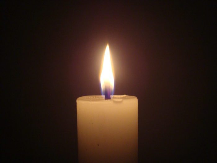 A single candle burns in a dark room.