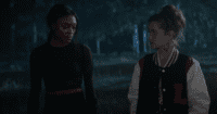 Two teenage girls walk alone in the dark, seemingly in deep conversation.