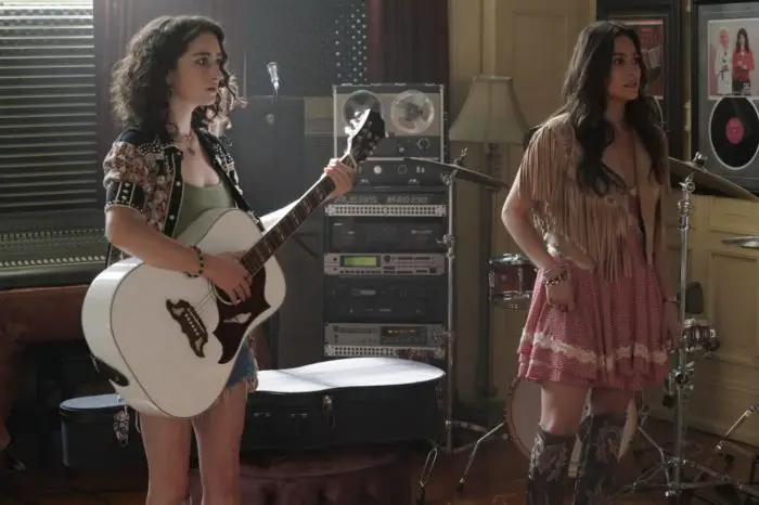 Jordan holds a guitar next to Leigh in Torn Hearts