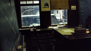 A dark old fashioned classroom with a chalkboard.