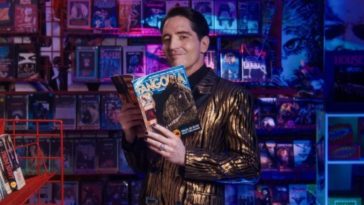David Dastmalchian stands in a video store holding a Fangoria magazine in a promo banner for the 2022 Fangoria Chainsaw Awards