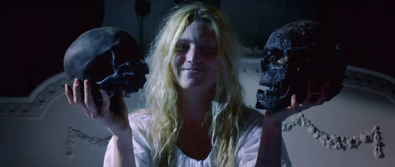 A crazy-looking woman holding two skulls