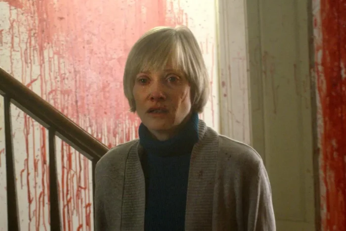 Barbara Crampton looking scared in a blood-soaked house