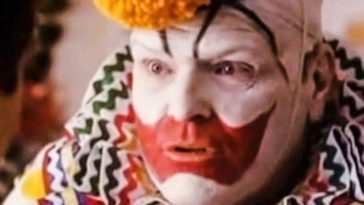 A closeup of a man in clown makeup and a colorful costume.