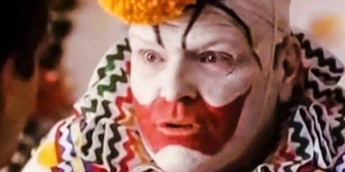 A closeup of a man in clown makeup and a colorful costume.
