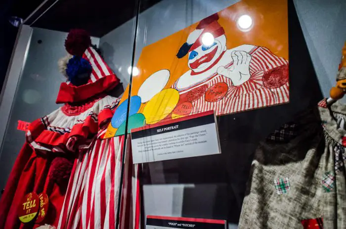 A clown painting and clown suit in a display case.