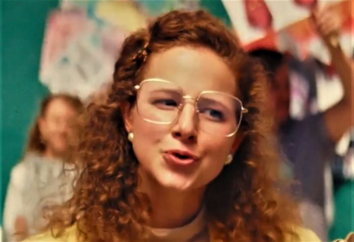 Shaina Schrooten as self-righteous religious pest Sally Mewbourne in the horror film Revealer, looking very 80s suburban with her large glasses and all around style.