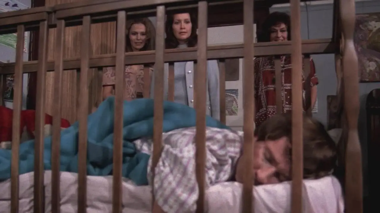 Baby sleeps in his crib with Mrs. Wadsworth and her daughters watching him.