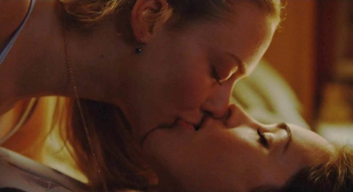 Two young women engage in a passionate kiss.