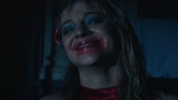 A woman smiles with smeared lipstick on her face.