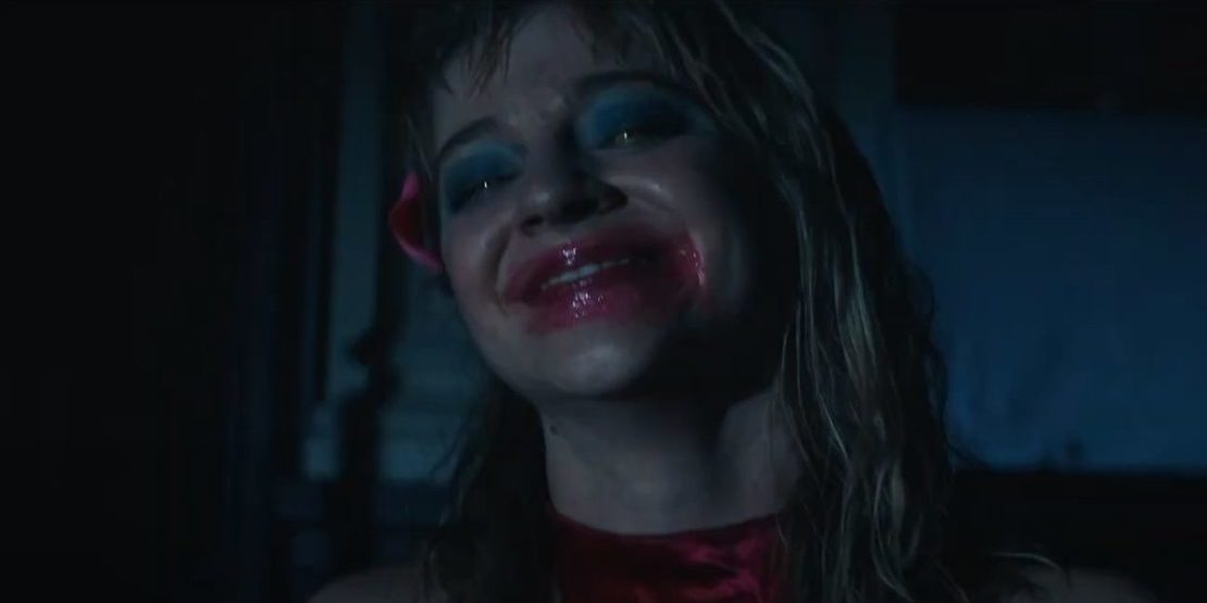 A woman smiles with smeared lipstick on her face.