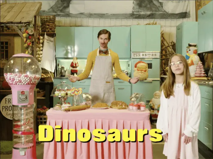 Uncle Bobbo and Purity are surrounded by sweets in a kitchenette setting in The Blood of the Dinosaurs