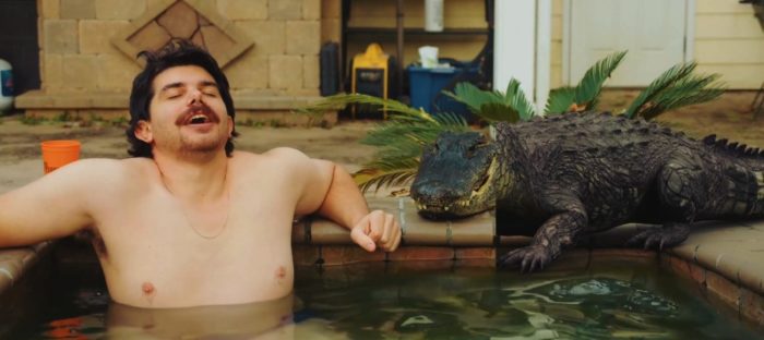 Paul Dale lounging in a hot tub about to be attacked by a very fake looking alligator in Sewer Gators