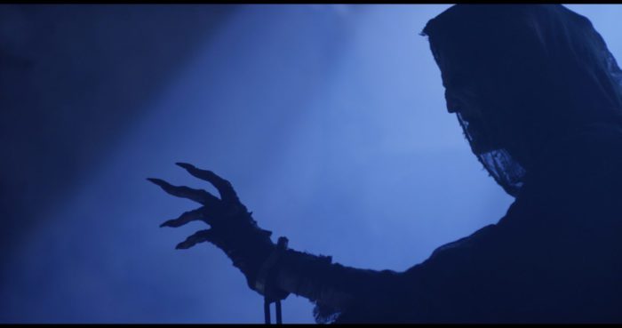 A veiled creature reaches out his hand in the moonlight in On the 3rd Day