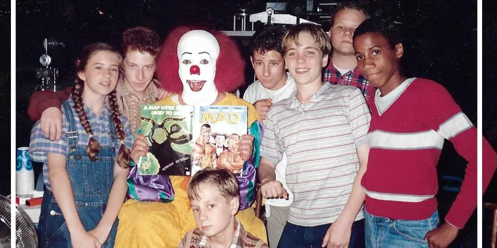 A cast photo shows the young kids gathered around Tim Curry in full Pennywise makeup in Pennywise: The Story of IT