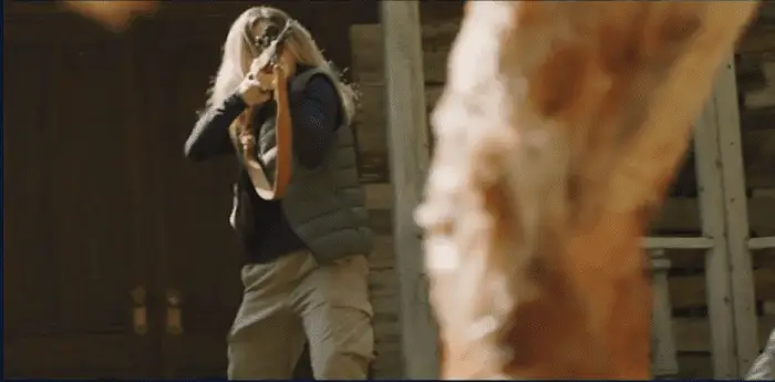 Meg aims a rifle at a fleshy creature walking toward her in The Breach