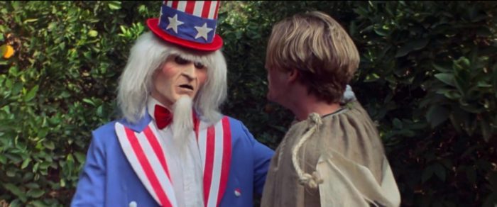 A man in an Uncle Sam costume grabs a boy in a sack racing sack