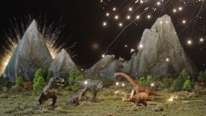 An Image of toy dinosaurs in a mountain scene as fiery sparks rain down on hem in The Blood of the Dinosaurs