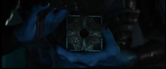 A closeup from the Hellraiser trailer shows two scarred pale hands with black fingernails caressing an ornate golden box