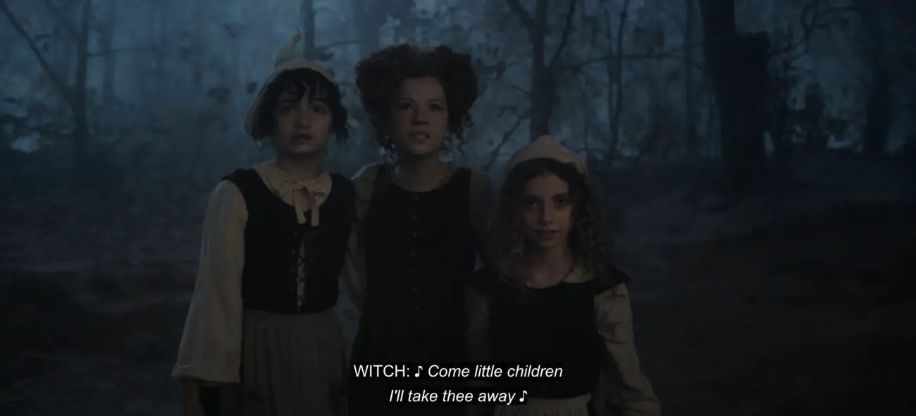 Young Sarah Sanderson (Juju Journey Brener) walks in front of her sisters, Young Winifred (Taylor Paige Henderson) and Young Mary (Nina Kitchen), enchanted by a voice singing, "Come little children, I'll take thee away," in the film, "Hocus Pocus 2" (2022).