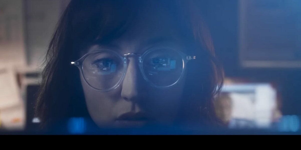 Alexandra looks at her computer, the screen reflects in her glasses