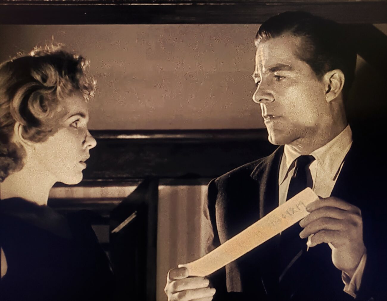 Performers Peggy Cummins and Dana Andrews reading the parchment slip containing the titular curse in Curse of the Demon