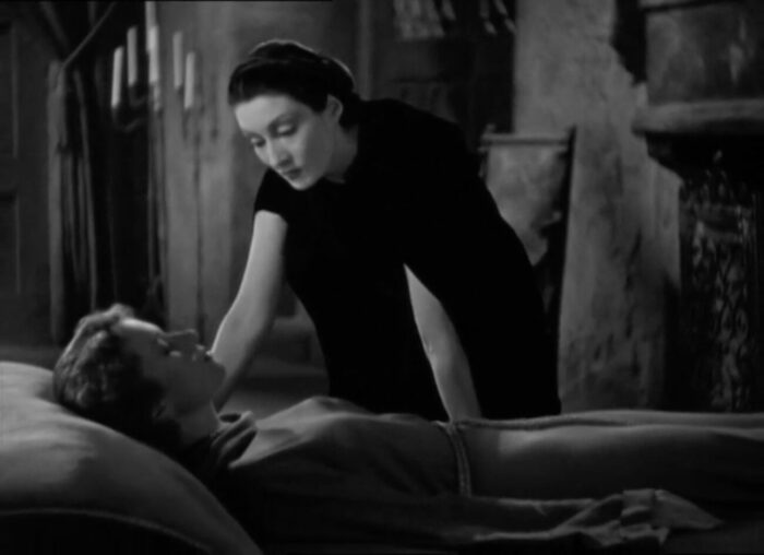 Countess Marya Zaleska (Gloria Holden) leans over a fainted Janet Blake (Marguerite Churchill), in the film, "Dracula's Daughter" (1936).