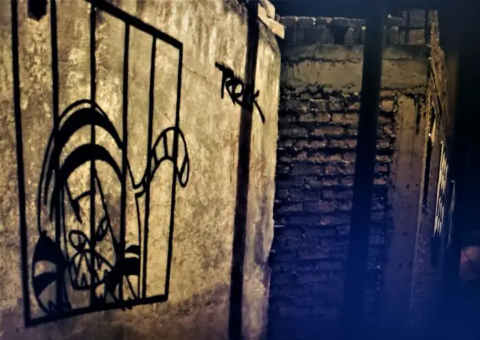 Childlike graffiti of a tiger in a cage spray painted on a wall
