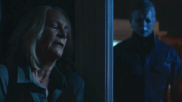 Laurie Strode leaning against a wall with Michael around the corner, walking her direction