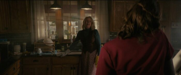 Laurie stands over a sink with oven mitts on talking to Allyson in Halloween Ends