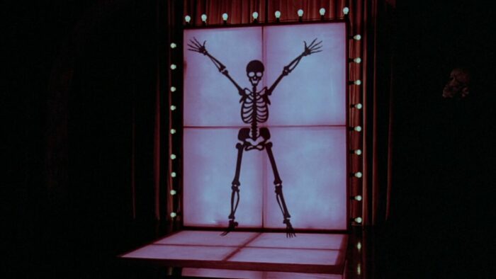 The animated outline of a skeleton presents itself on a well-lit stage in The Monster Club