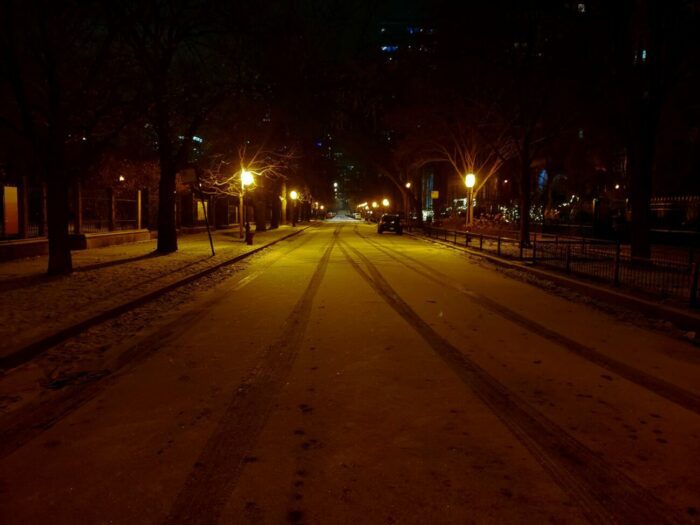 Chicago's Prairie Ave., lit by the orange sodium glow of street lamps and covered in snow. The street is empty save for parked cars.