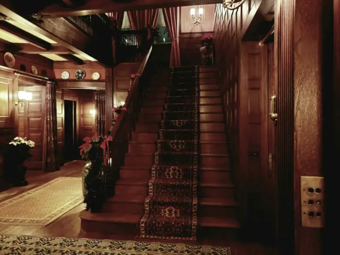 A luxurious wooden staircase inside the Glessner house, adorned with holly for Christmas.