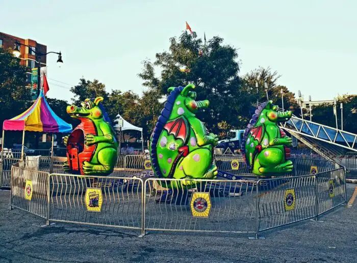 Unattended, empty dragon themed amusement park rides set up in a parking lot for a street carnival.