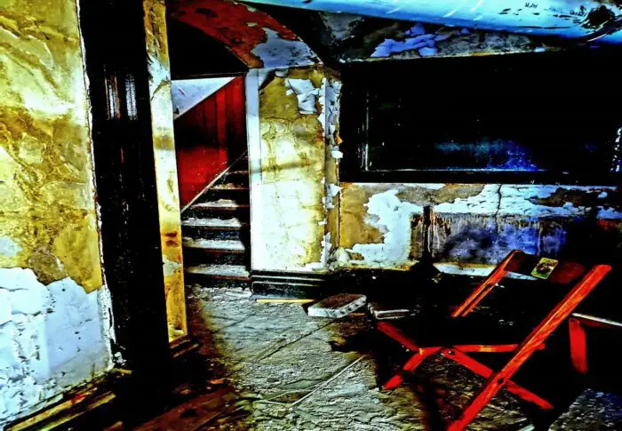 A vacant chair in an empty room in a deteriorating ruined building