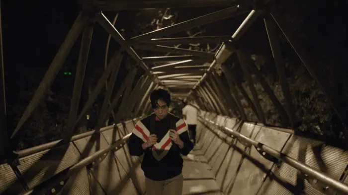 Valeria walks on a bridge at night
