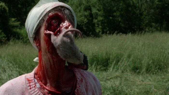 a rat crawls over a woman's decaying face. Her eye protruding from its socket.