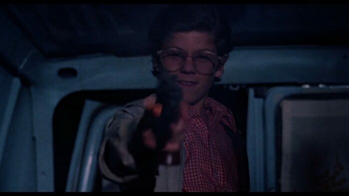 a boy holds a gun straight into the camera